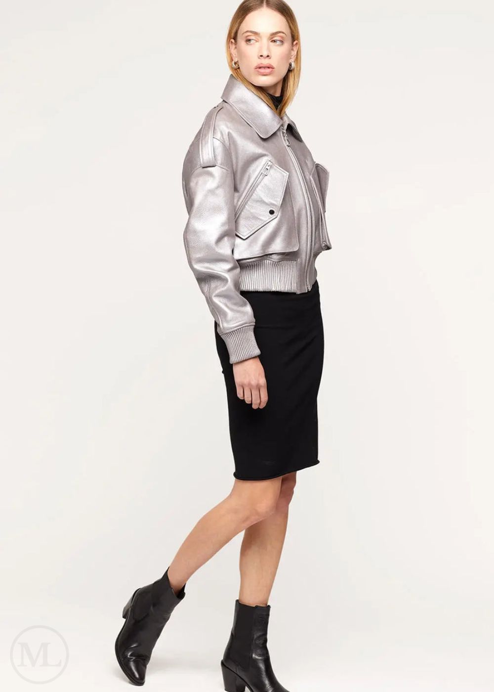 Woman wearing a silver leather bomber jacket, black skirt, and black boots on a white background