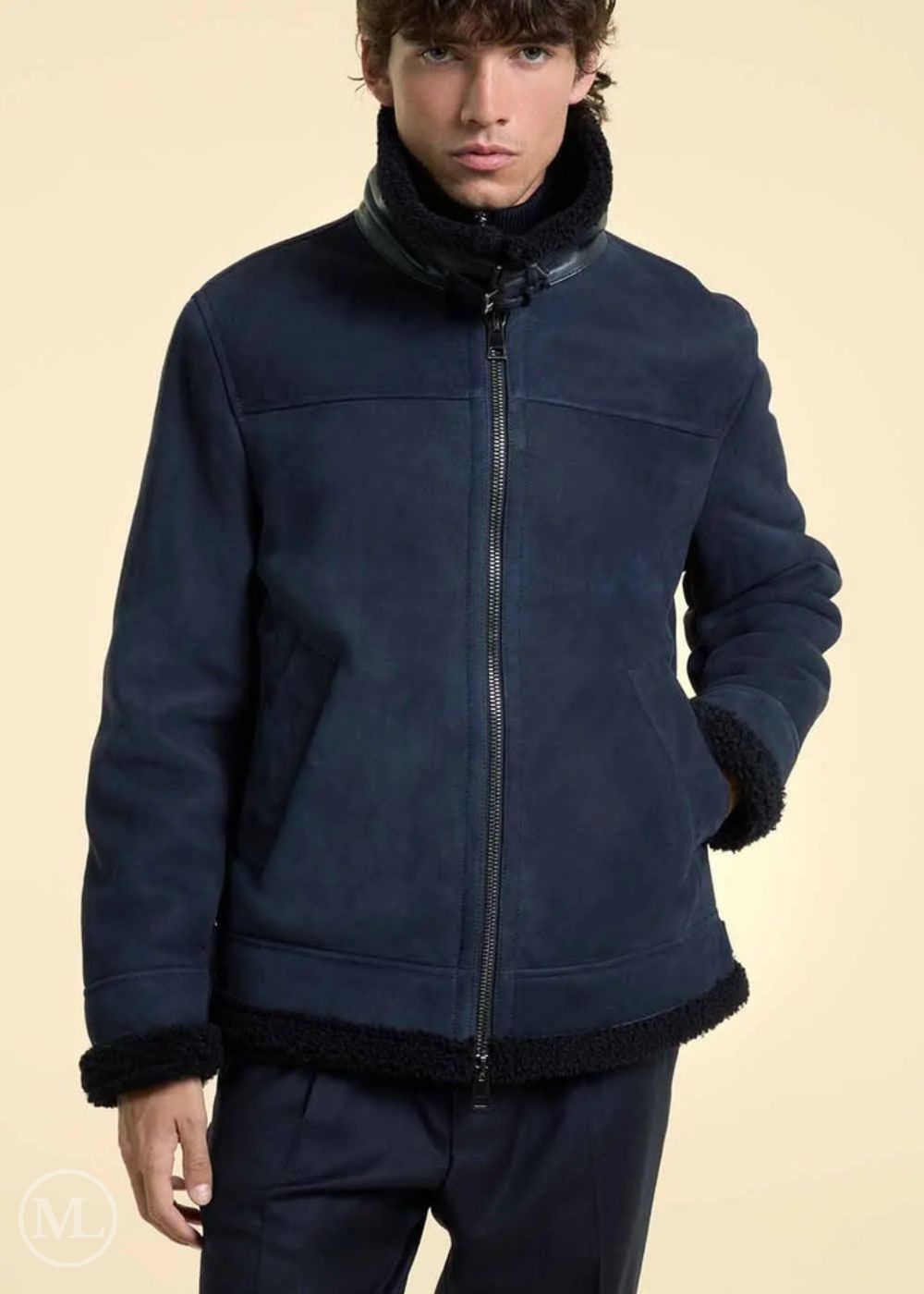 Man wearing a navy blue suede jacket with black trim on a beige background