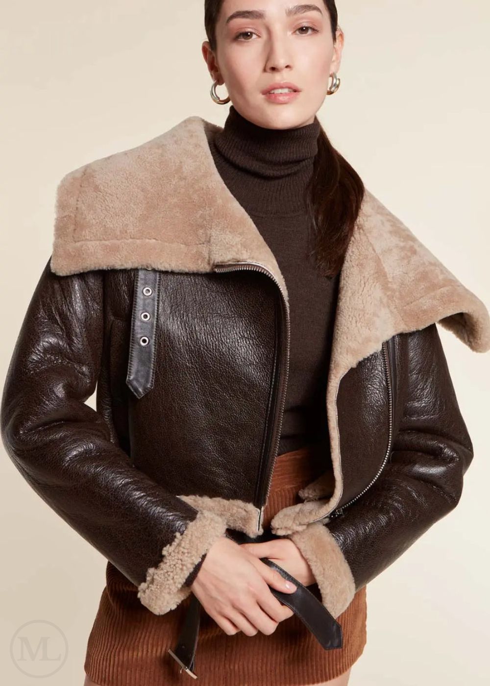 Woman wearing a dark brown aviator jacket with beige shearling collar and cuffs on a beige background