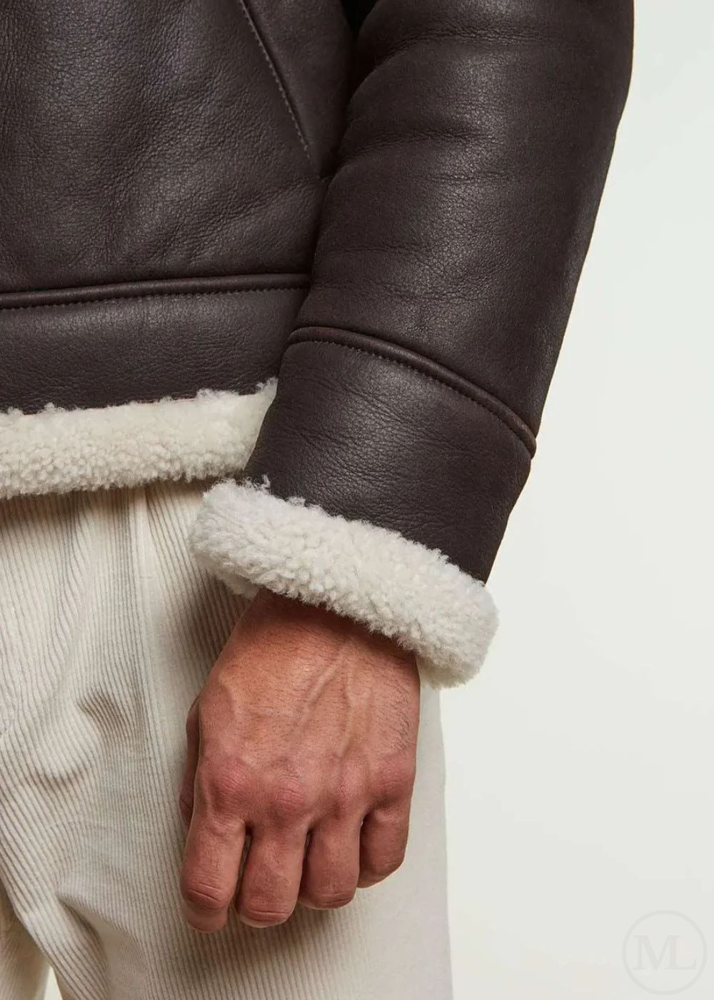 Close-up of a man wearing a brown leather aviator jacket with white fleece lining on a light background